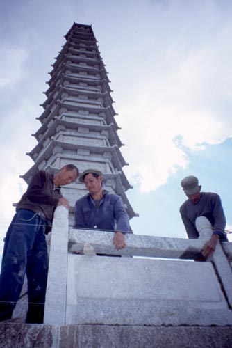 Stonemasons carefully piece together a new wall around one of a pair of pagodas.