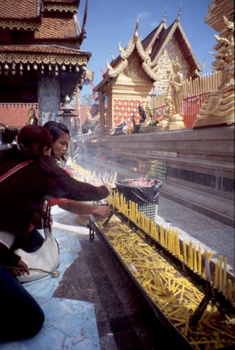 Lighting candles at one of the many shrines that surround the central stupa.